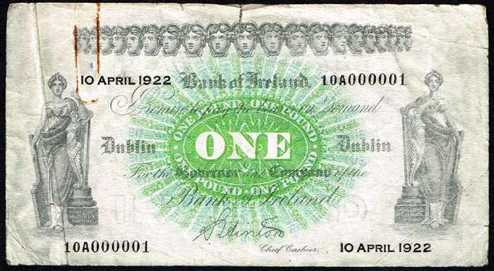 1922 Bank of Ireland One Pound, 10 April 1922, serial number 10A000001. Signed S. Hinton. Tear at top centre, rustmarks from paper clip, about very fine